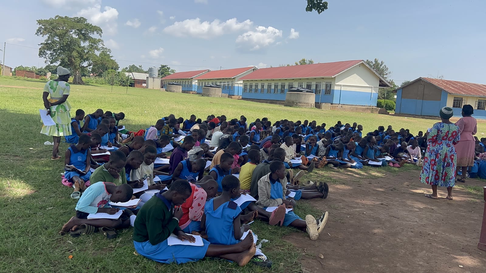 Students seated on the grounds of Buyanga Primary School completing the June 2026 menstrual health assessment
