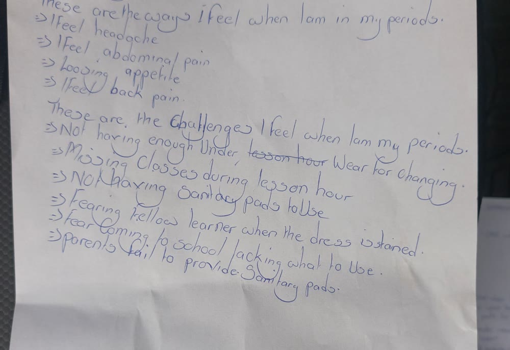 An anonymized handwritten student account describing pain, missing classes, lack of pads, and fear of staining a school dress