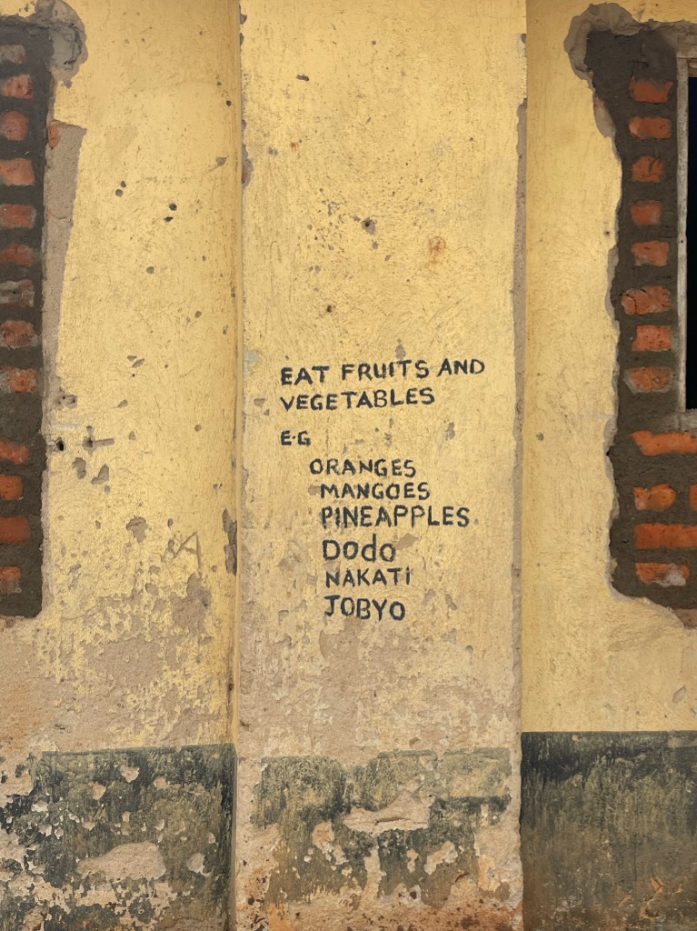A hand-painted yellow wall in Uganda reminding children to eat fruits and vegetables