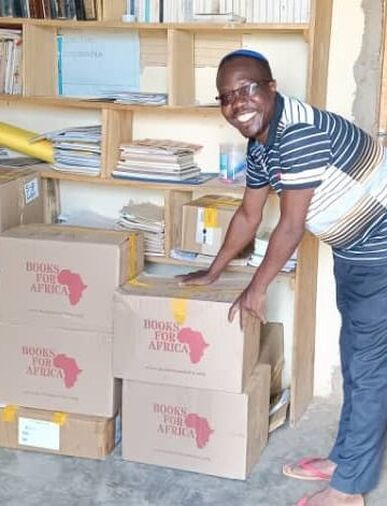 GVC partner rabbi organizing the newly arrived book boxes next to school library shelves
