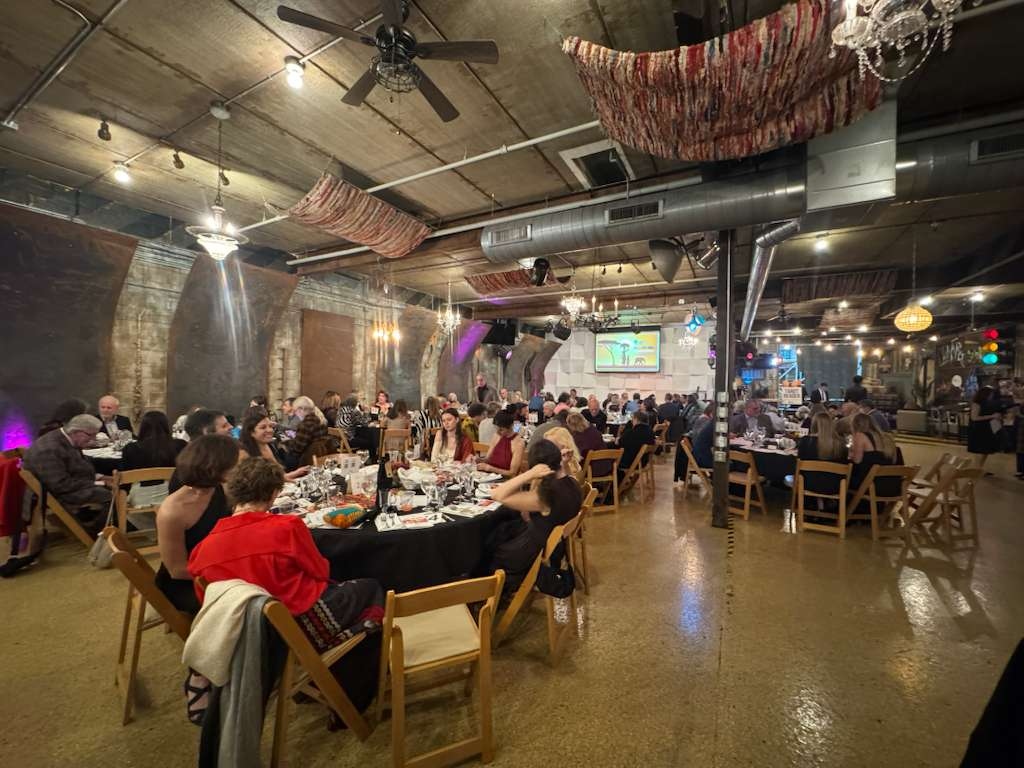 Gala guests dining and celebrating together under the warm barn lights