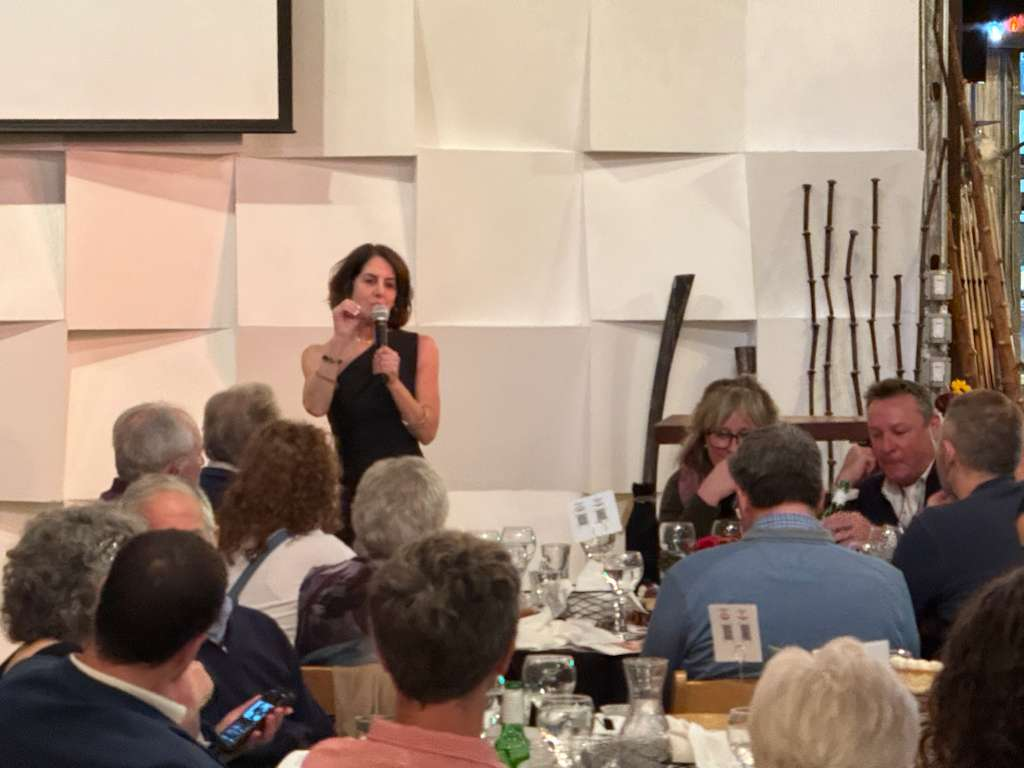 A presenter speaking on stage to the dinner guests at the Into the Wild Gala