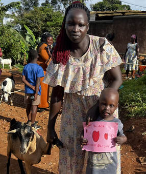 A mother and child holding a thank you card alongside their new goat